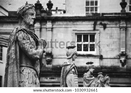 Stone statues of Roman warriors in Roman Baths complex in Bath, England, UK. City of Bath  is a UNESCO World Heritage Site. Black and white photo.