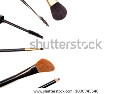 Makeup brushes, pencil, and a mascara applicator, shot from above on a white background with copy space. A template for a makeup artist's business card or flyer design