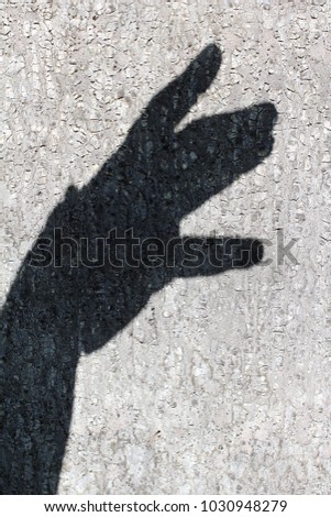 Dark shadow of a male hand on a concrete wall