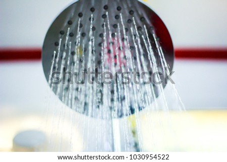 De focused Running water in the shower. Big shower head Bathroom, Modern bathroom interior. Shower head with water stream. Closeup of a shower head with sprinkling water, blue toned photo.