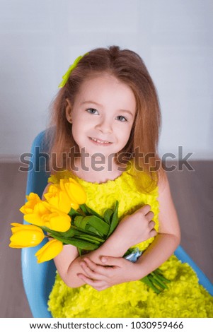 Beautiful little girl with a bouquet of tulips. Spring and summer portrait of cute child holding flowers.