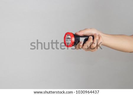 Hand holds flashlight isolated on white background.