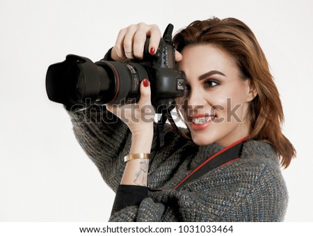 Pretty Young smiling girl taking a photo with a professional DSLR camera on white isolated background