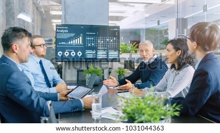 Board of Directors Has Annual Meeting, Diverse Group of Business People in the Modern Conference Room Discuss Statistics and Work Results. In the Background Projector Showing Company Growth. Royalty-Free Stock Photo #1031044363