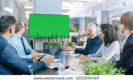 Diverse Group of Successful Business People in the Conference Room with  Green Screen Chroma Key TV on the Wall.  They Work on a Company's Growth, Share Charts and Statistics.