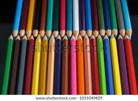 Pile of multicolored wooden crayon isolated on the black background with the reflection.