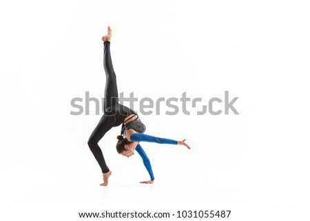 The portrait of beautiful young brunette woman gymnast training calilisthenics exercise with acrobatic element on white studio background. Art gymnastics concept. Caucasian model in full height