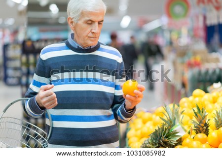 Senior man choosing fruit to buy at supermarket