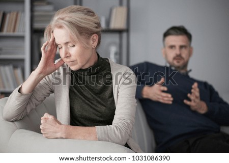 Depressed and tired wife with a headache in the middle of a conflict with a jealous husband Royalty-Free Stock Photo #1031086390