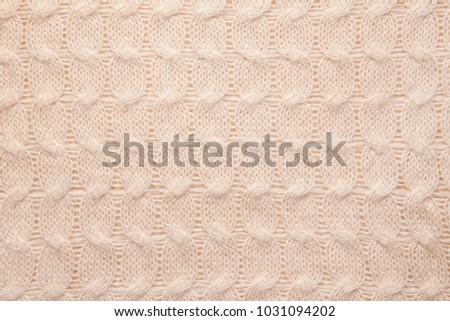 Texture of a beige knitted sweater close-up.