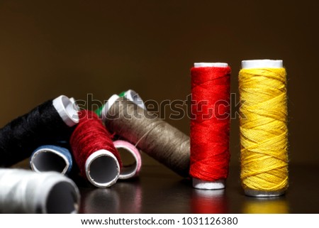 Background with a lot of colorful coils with threads. Bobbins are stacked in three rows, one on the other. The winding is erratic. Multicolored threads.