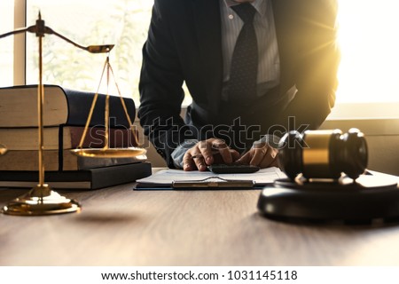Male lawyer working with calculator and wooden gavel on tabel in courtroom. justice and law ,attorney, court judge, concept.