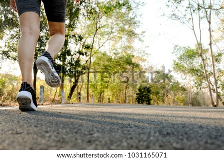 Sports woman legs in running movement, Close up picture of feet of young woman relax walking in the park on the great holiday, Healthy lifestyle concept.