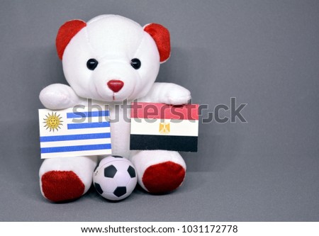 Teddy bear holding Uruguay and Egypt Flag with a football