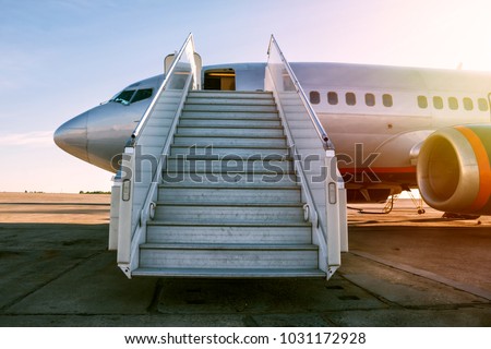 Passenger airplane with a boarding steps in the morning sun Royalty-Free Stock Photo #1031172928