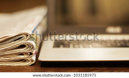 Newspapers and computer. Laptop and daily papers on the table. Fresh news by  paper or by electronic device, different ways of communication. Source of information, actual data on pages or on screen  Royalty-Free Stock Photo #1031185975