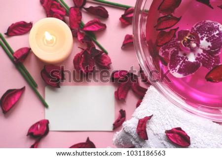 Pink background with dried petals, candle, orchid flower and copy space for your text; beauty, spa or wellness background