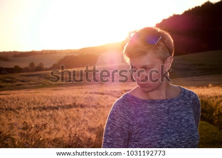 Woman Silhouette at sunset against the sun and a corn field with a colorful orange sky and hills in the background