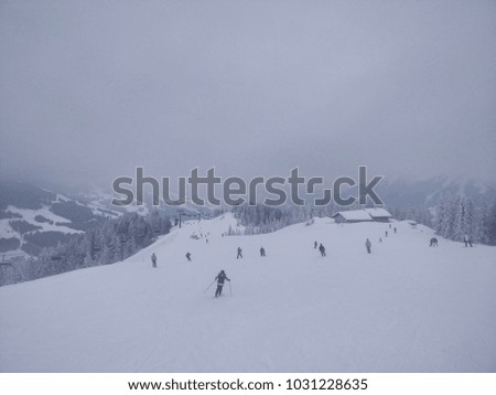 Winter mountains panorama on a foggy day with many skiers and snowboarders, Austrian Alps