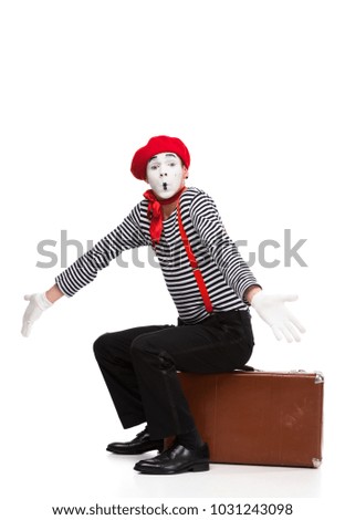 mime sitting on brown suitcase and showing shrug gesture isolated on white