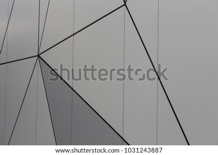 Close up outdoor view of the detail of a modern building facade. Pattern with polygonal gray shapes drawn by dark lines. Geometric surface made of various triangles and polygons. Abstract image.  