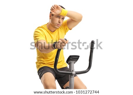 Tired young man exercising on a cross-trainer machine isolated on white background