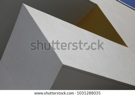 Close up outdoor view of a white painted balcony of a modern building in a french city. Geometric colored forms, in white, gray and yellow. Abstract urban exterior image with points, lines and angles.