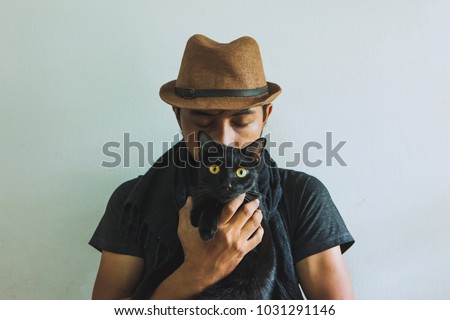 Portrait of a  Love to animals with black cat.black cat  in man hands.Asian Guy Kissing a Cat