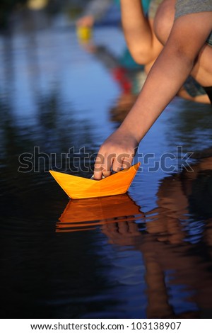 paper ship in children hand, boy play with paper boat in water puddle 