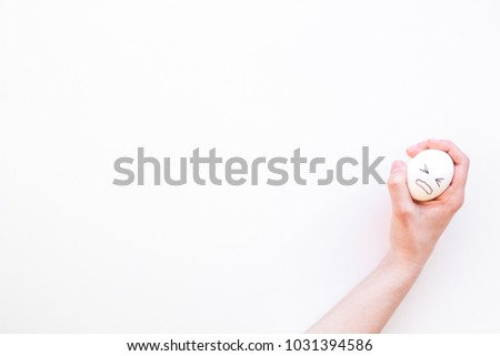 Emotion management concept. Suppression anger. Angry face drawn on egg. White background top view copy space