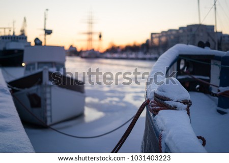Selective focus on mooring bollard on boat covered by snow during winter sunset