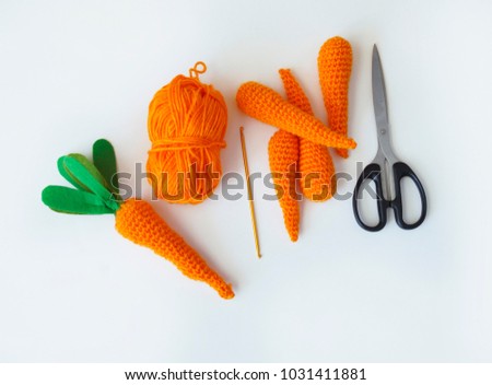Easter. Knitted carrot toy. The process of creating the carrot. Orange threads. Green cloth, scissors, hook on wooden tray.