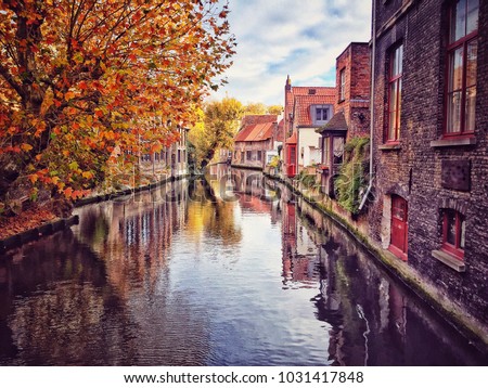 Bruges Belgium, Typical brick houses by canal or water channel in Brugge or Bruges city of Belgium under beautiful blue sky in autumn. Europe destination photo concept with copy space