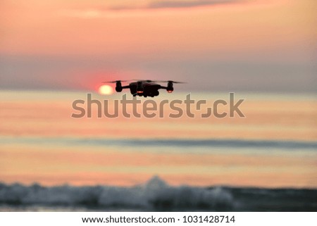 Drone flying in the sunset at beach  .The drone with the professional camera takes pictures.