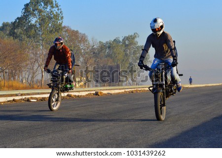 Two stunt motorcycle riders making stoppie near Pune