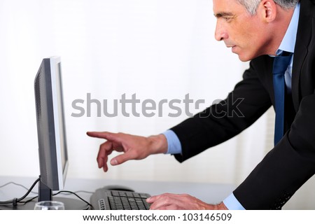Portrait of a elegant hispanic business man pointing the computer screen at the office