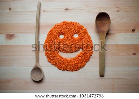 On a wooden surface is red or orange lentils in the form of a smile.