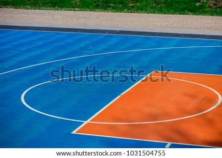 Abstract, blue background of newly made outdoor basketball court in park. Visible asphalt texture, freshly painted lines.