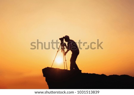 Travel concept with of photographers standing on mountain's top with camera and tripod and taking photo shots.