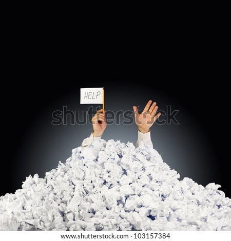 Person under crumpled pile of papers with hand holding a help sign Royalty-Free Stock Photo #103157384