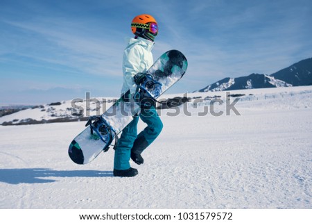 one snowboarder with snowboard walking on the snowobard piste in winter mountains