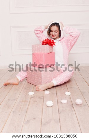 winter, christmas, holiday, sweets, birthday, celebration and children concept- Cute little girl pajama with sweets sitting on the floor, happy childhood concept. girl gifts, soft dog, soap bubbles.
