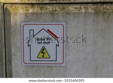 A label on an electricity  meter box informing that solar panels are on the roof of a house.