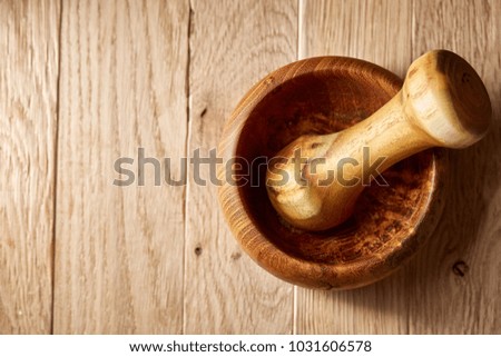 Top view close-up picture of wooden pestle and mortar on brown rustic wooden background, shallow depth of field