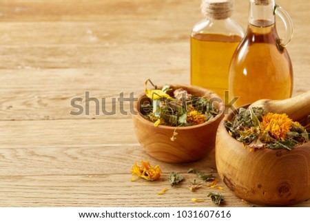 Picturesque composition of oil jars, pestle and mortar with motley grass over wooden background, selective focus.
