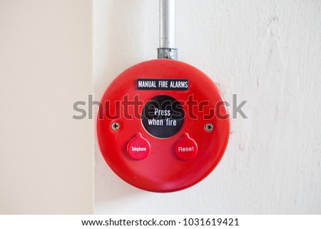 Red fire alarm on white wall