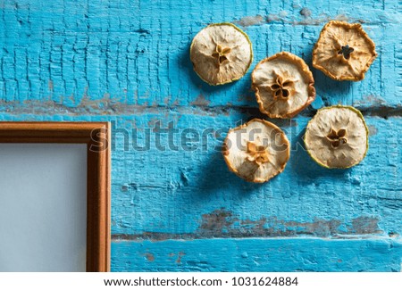 wooden photo frame on old blue wooden textured wall with empty place for text or image with slices of dried apple design