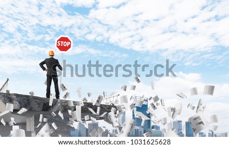 Rear view of engineer in helmet holding stop sign while standing among flying papers on broken bridge with cityscape on background. 3D rendering.