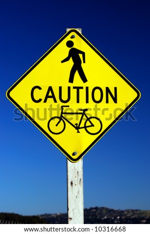 Road sign - Caution - Pedestrian and Bicycle Traffic on a blue sky background