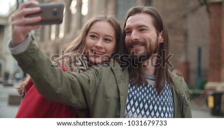 Young beautiful couple taking selfie in a city.